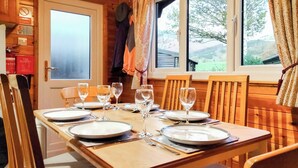 A wooden dining table set for four with plates, glasses, and cutlery. - 3 bedroom accommodation in Keswick (Keswick)