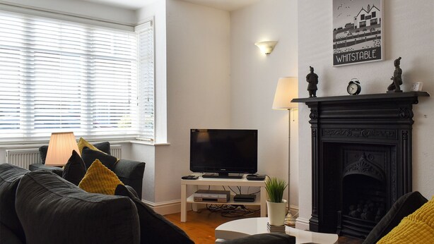 Un salon avec une cheminée, un téléviseur et un canapé avec des coussins.