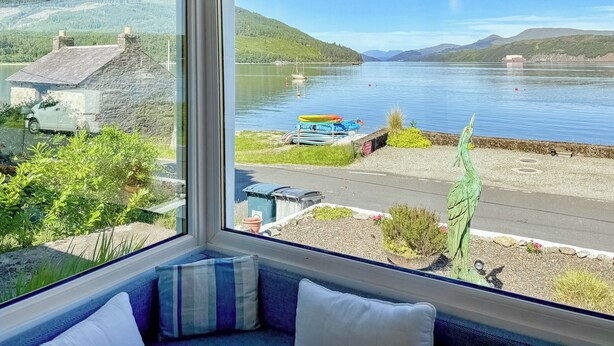 A room with a large window overlooking a lake, a bench, and a seating area with cushions. - 2 bedroom accommodation in Ardentinny near Dunoon (Ardentinny near Dunoon)