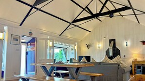 A room with a wooden floor, a sofa, a table with metal legs, and a ceiling with exposed beams. - 2 bedroom accommodation in Ardentinny near Dunoon (Ardentinny near Dunoon)