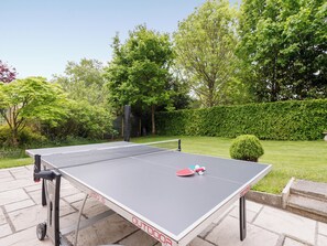 An outdoor ping pong table with a net, surrounded by a garden with trees and a hedge. - 3 bedroom accommodation in Wareham (Wareham)