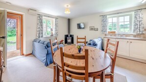 A cozy living room with a sofa set, a wooden dining table, and a TV mounted on the wall. - Stable Cottage - 26032 (Wark, near Hexham)