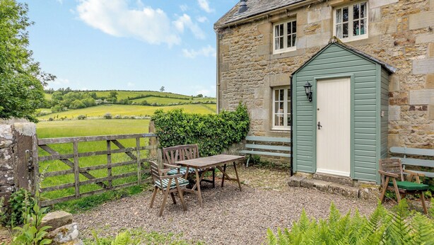A stone cottage with a green door, a wooden table, and a bench. - Stable Cottage - 26032 (Wark, near Hexham)