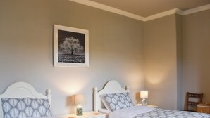 A bedroom with two beds, each with a patterned bedspread, a bedside table with a lamp, and a framed picture on the wall. - 2 bedroom accommodation in Skipton (Skipton)