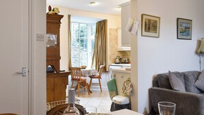 A dining area with a table set for two, a sofa, and a kitchen in the background. - 2 bedroom accommodation in Skipton (Skipton)