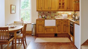 A kitchen with wooden cabinets, a sink, a stove, and a dining area with chairs and a table.