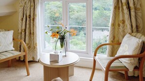 A room with two wooden chairs, a round wooden table, and a window with curtains.