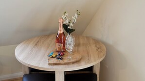 Ein runder Holztisch mit einer Martini Rosé Flasche, einem Glas und einer Vase mit weißen Orchideen.