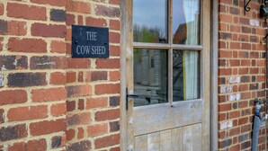 Un mur de briques sur lequel est affiché un panneau indiquant : « The Cow Shed ».