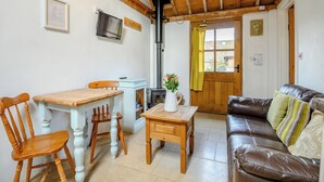 Une pièce chaleureuse avec une table en bois, des chaises, un canapé, une télévision et une cheminée.
