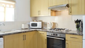 Uma cozinha moderna com armários de madeira, fogão de aço inoxidável, micro-ondas e cafeteira.