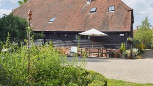 A rustic barn-style building with a sloped roof, a chimney, and a gravel driveway. - 2 bedroom accommodation in Burwash (Burwash)