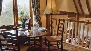 A dining area with a wooden table set for two, a vase with flowers, and a lamp. - 2 bedroom accommodation in Burwash (Burwash)