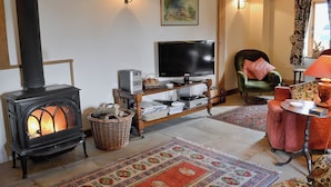A cozy living room with a fireplace, a television, and a comfortable seating area. - 2 bedroom accommodation in Burwash (Burwash)