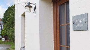A house with a sign reading "Ty Capel Seion" and a window with a wooden frame. - A beamed, character cottage situated just 100 yards from the River Teifi. (St Dogmaels near Cardigan)