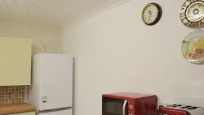 A kitchen with a white refrigerator, a red microwave, and a toaster on a wooden countertop. - A beamed, character cottage situated just 100 yards from the River Teifi. (St Dogmaels near Cardigan)