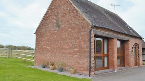 A brick building with a sloped roof, large windows, and a door.