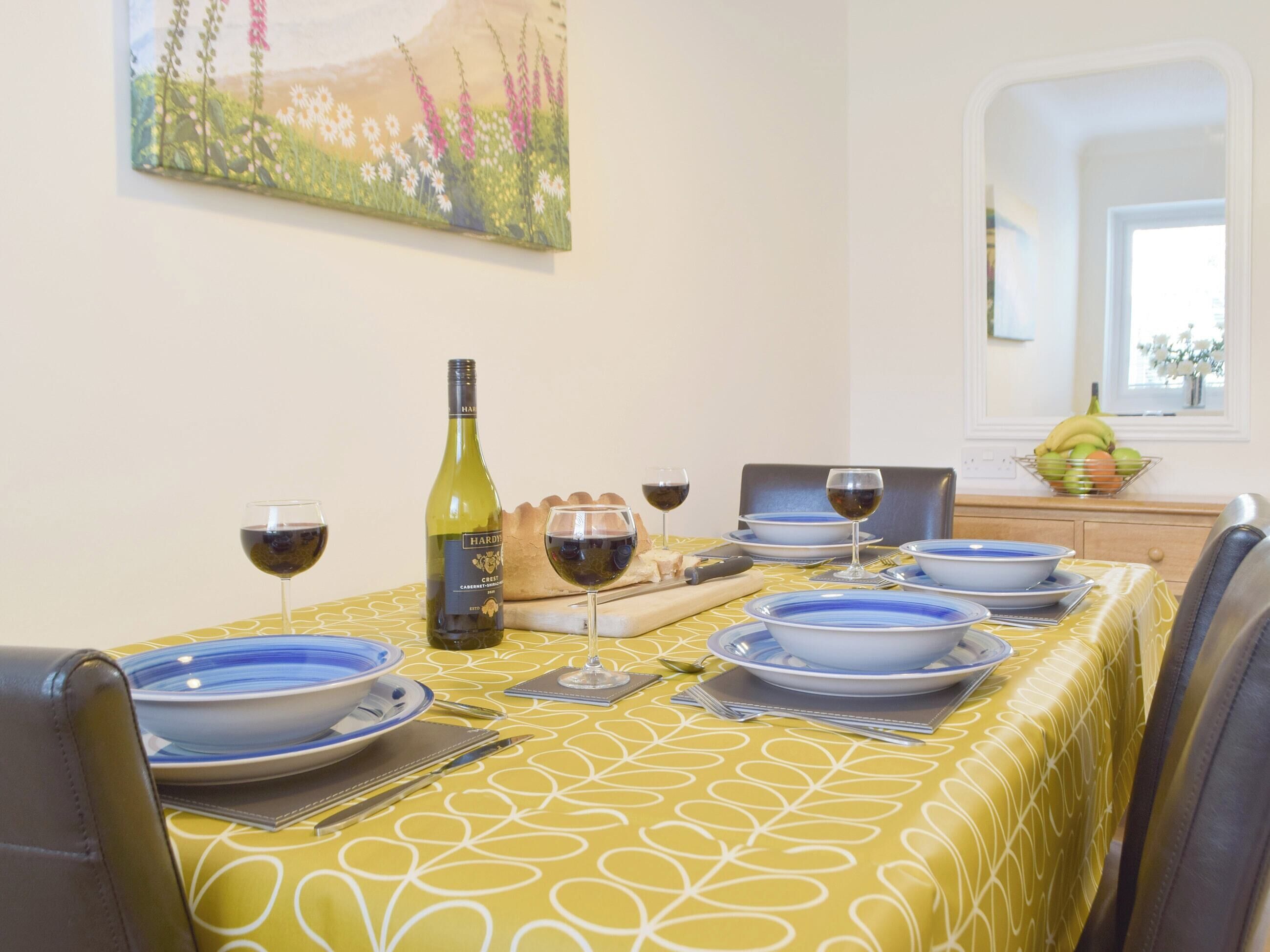 Une table à manger dressée avec des assiettes bleues, des verres à vin et une bouteille de vin.