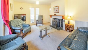 A living room with a fireplace, a television, and a sofa. - Super location within woodland and a SSSI. (Glenridding, near Penrith)