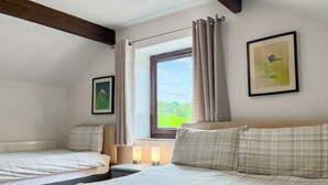 A bedroom with two beds, a window with curtains, a radiator, and a framed picture on the wall. - Honeysuckle Cottage - 27880 (Matlock)