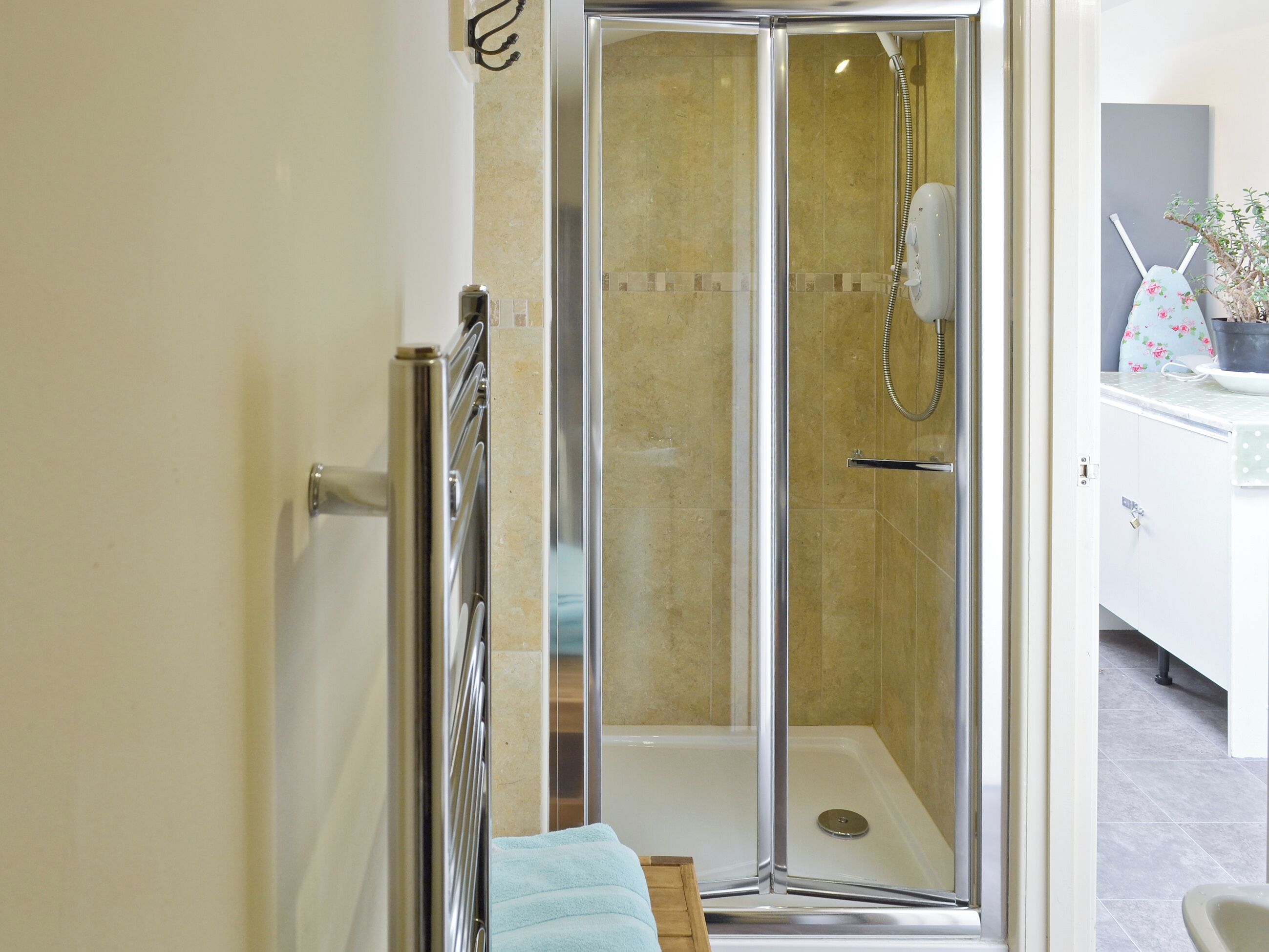 A modern bathroom with a glass-enclosed shower, a towel rack, and a sink area.