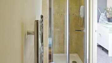 A modern bathroom with a glass-enclosed shower, a towel rack, and a sink area.