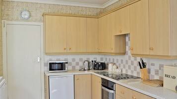 A compact kitchen with wooden cabinets, a microwave, a toaster, and a refrigerator.