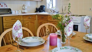 Een eettafel gedekt met borden met een bloemmotief, een kaars en glazen.