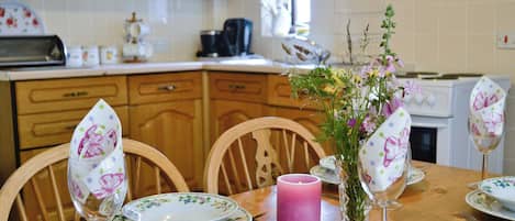 Una mesa de comedor dispuesta con platos de estampado floral, una vela y cristalería.