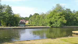 A tranquil lakeside setting with a gazebo, a wooden dock, and lush greenery.