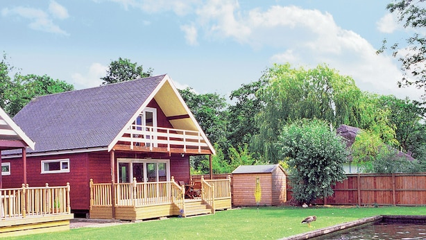 A red house with a porch and a small shed.