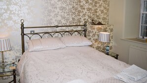 Quarto com cama, duas luminárias de cabeceira, mesa de cabeceira e janela com persianas.