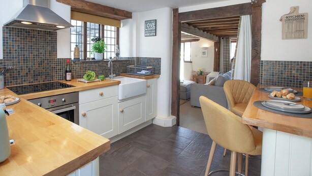 A modern kitchen with a large island, a built-in oven, and a stainless steel range hood.