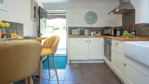 A kitchen with white cabinets, a clock, a stove, and a microwave.