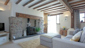 A cozy living room with a stone fireplace, a sofa, and a television.