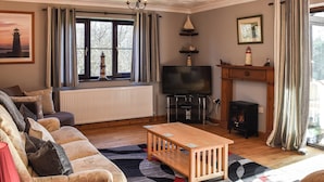 A cozy living room with a sofa, a wooden coffee table, a fireplace, and a television. - 3 bedroom accommodation in Walcott (Walcott)