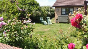 A garden with a brick house, green lawn, and outdoor furniture. - 3 bedroom accommodation in Walcott (Walcott)