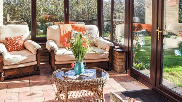 A sunlit patio with wicker furniture and a glass door leading to a garden. - 3 bedroom accommodation in Walcott (Walcott)