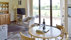 Un espace repas comprenant une table ronde, des chaises, un téléviseur et une vue sur l’extérieur.