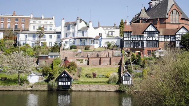 Une ville riveraine qui abrite des bâtiments historiques, notamment une église dotée d’un clocher et une maison de style Tudor.