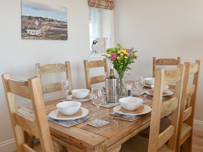 A wooden dining table set with white bowls, wine glasses, and a bottle of wine. - Harbourside Apartment (Anstruther)