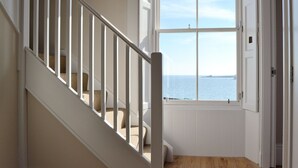 A staircase leading to a room with a view of the sea, a door, and a window with blinds. - Harbourside Apartment (Anstruther)