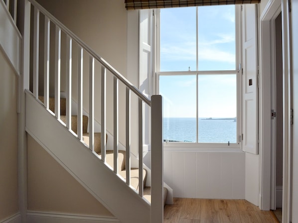 A staircase leading to a room with a view of the sea, a door, and a window with blinds. - Harbourside Apartment (Anstruther)