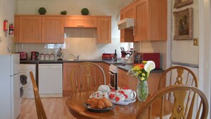 Una cocina con armarios de madera, una mesa de comedor con sillas y una mesa de centro con croissants y un jarrón de flores.