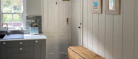 A kitchen with a sink, cabinets, and a wooden bench.