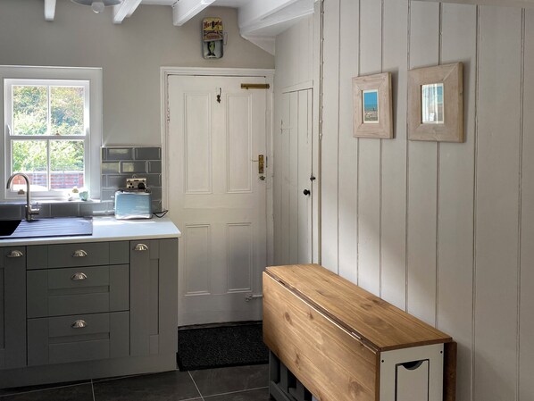 A kitchen with a sink, cabinets, and a wooden bench.