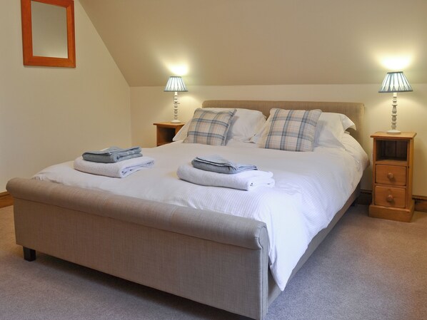 A neatly made bed with folded towels, two bedside tables with lamps, and a wooden nightstand. - 1 bedroom accommodation in Ulrome near Bridlington (Ulrome near Bridlington)