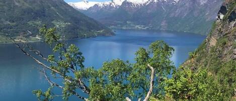 A mountainous landscape with a lake, trees, and snow-capped peaks.