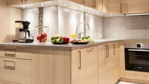 A modern kitchen with wooden cabinets, a built-in oven, and a coffee machine on the counter.