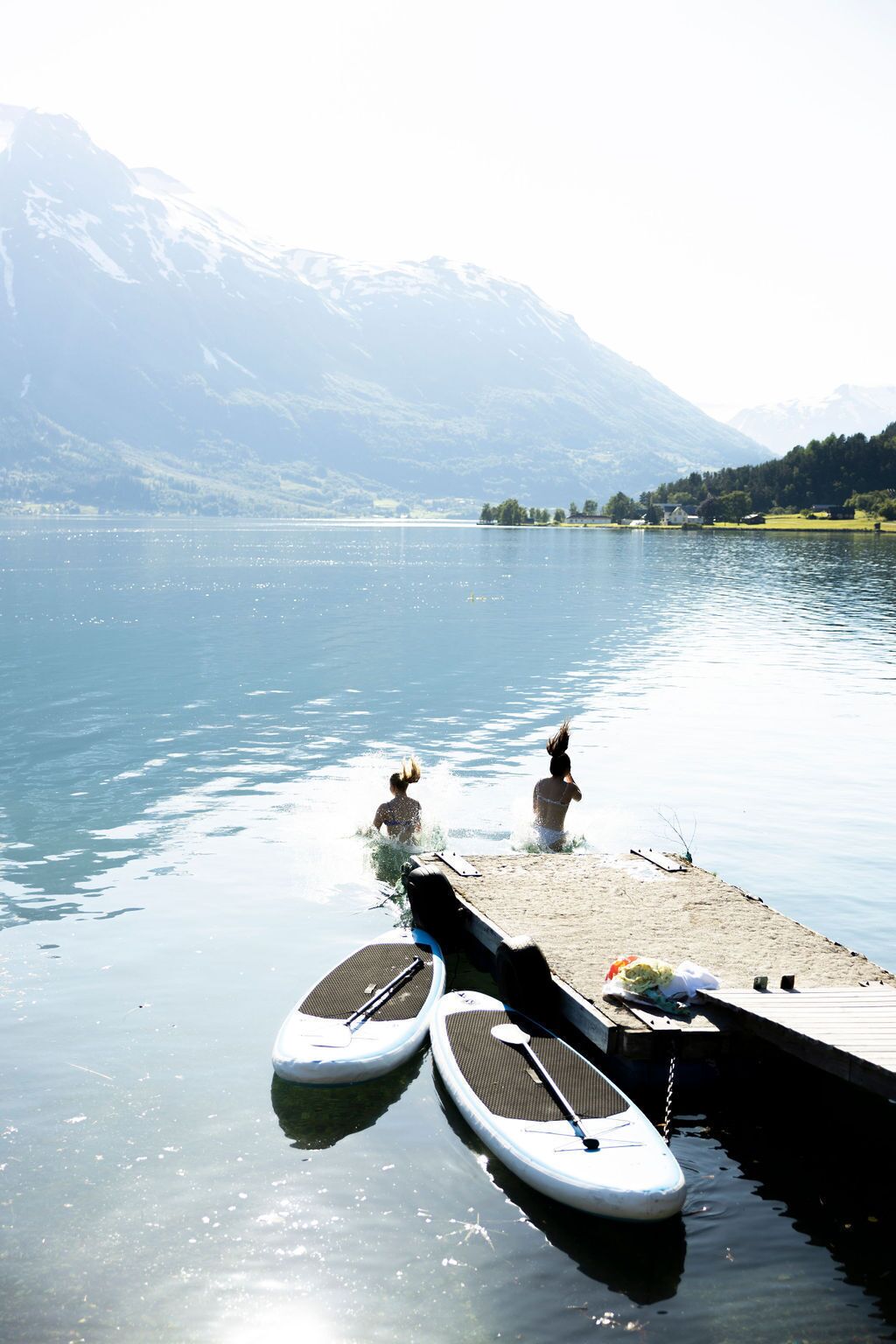 Um lago com pranchas de remo atracadas na margem, rodeado por montanhas.
